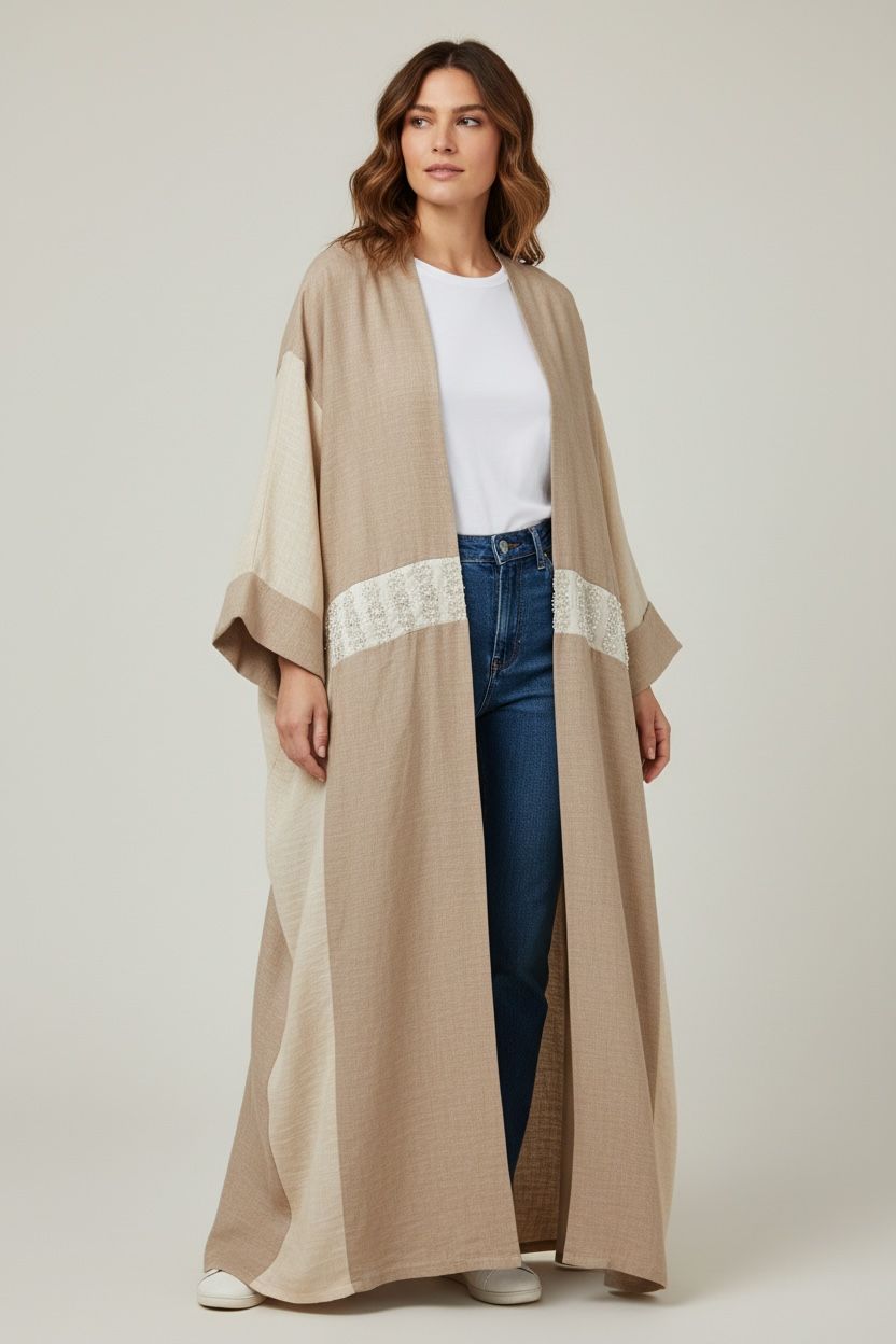 Woman wearing a long beige cardigan with white trim on a plain background